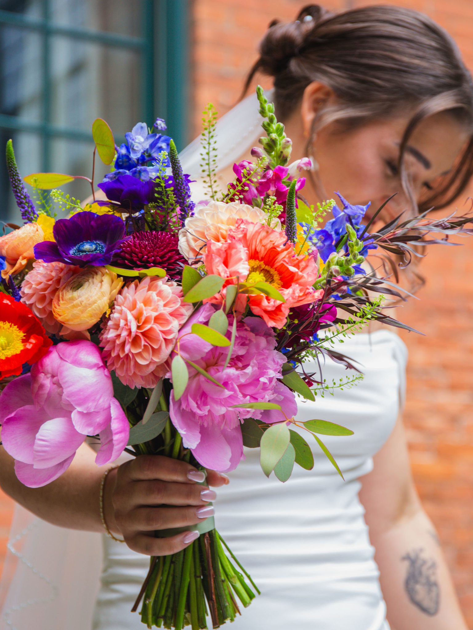 Close-up of Gabrielle's colorful bridal bouquet with peonies, dahlias, and delphinium