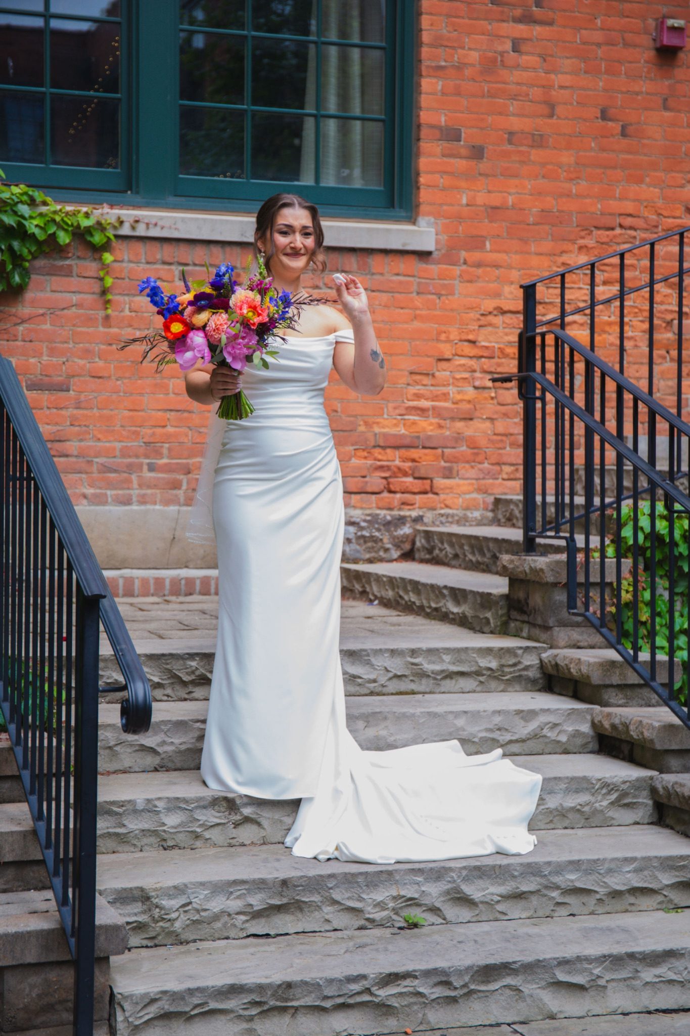 Gabrielle overcome with emotion on the staircase during her first look reveal, bouquet in hand
