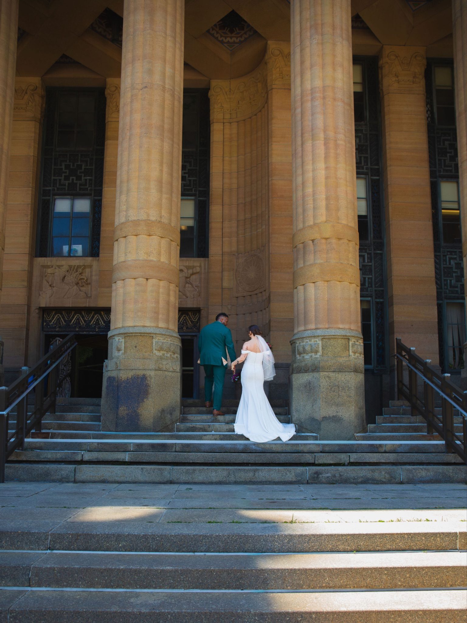 Gabrielle and Chandler walking hand in hand into Buffalo City Hall for portraits