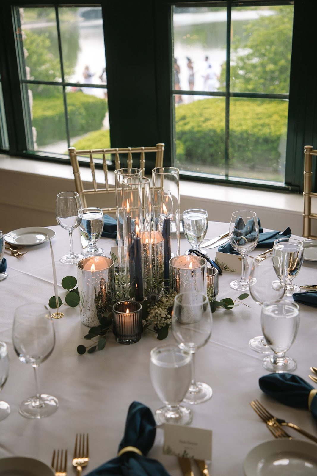 Reception table with mercury glass candle holders and greenery, overlooking the venue lawn