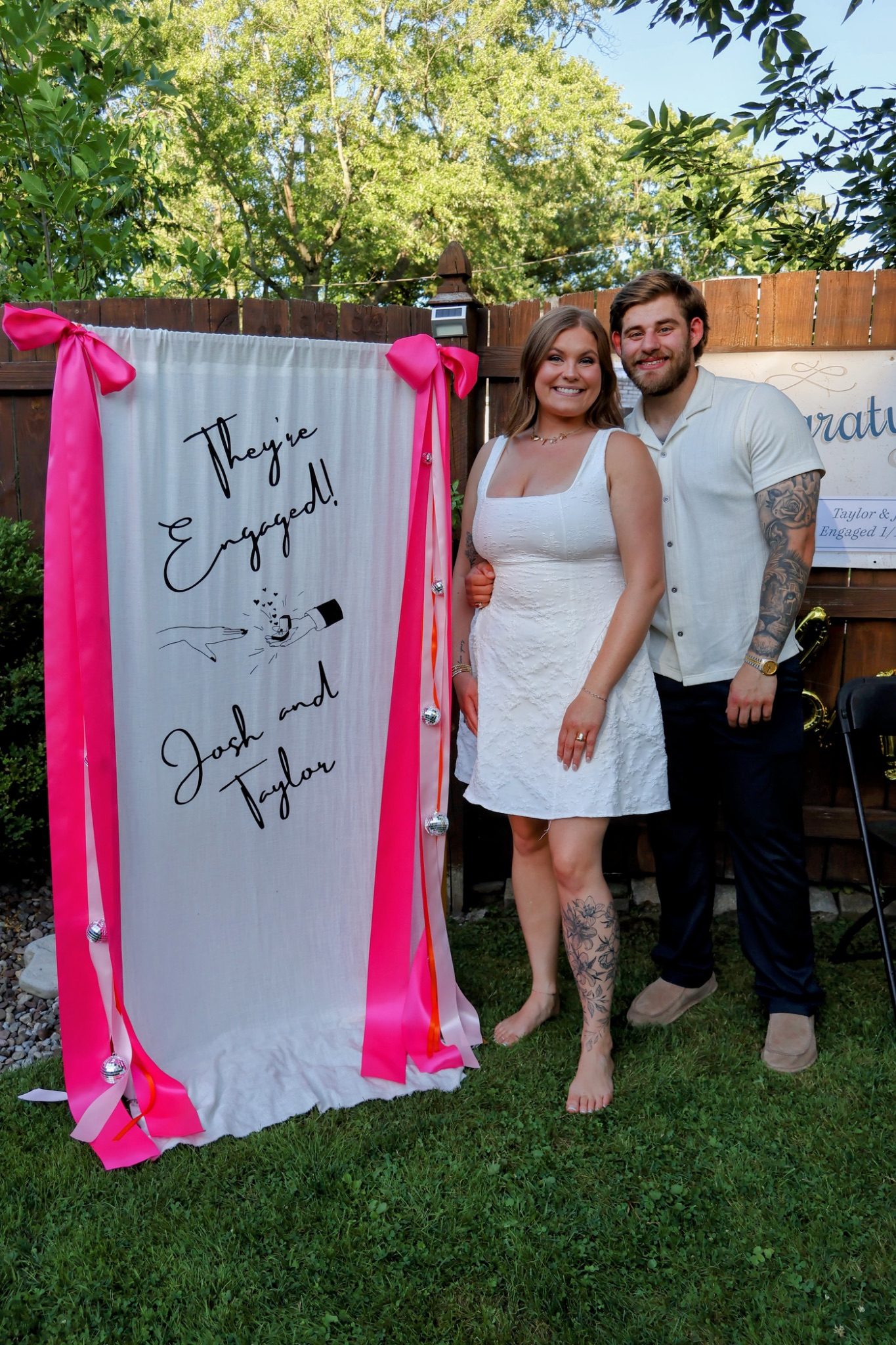 A couple celebrating in front of a custom engagement banner Farkas Events designed for their party