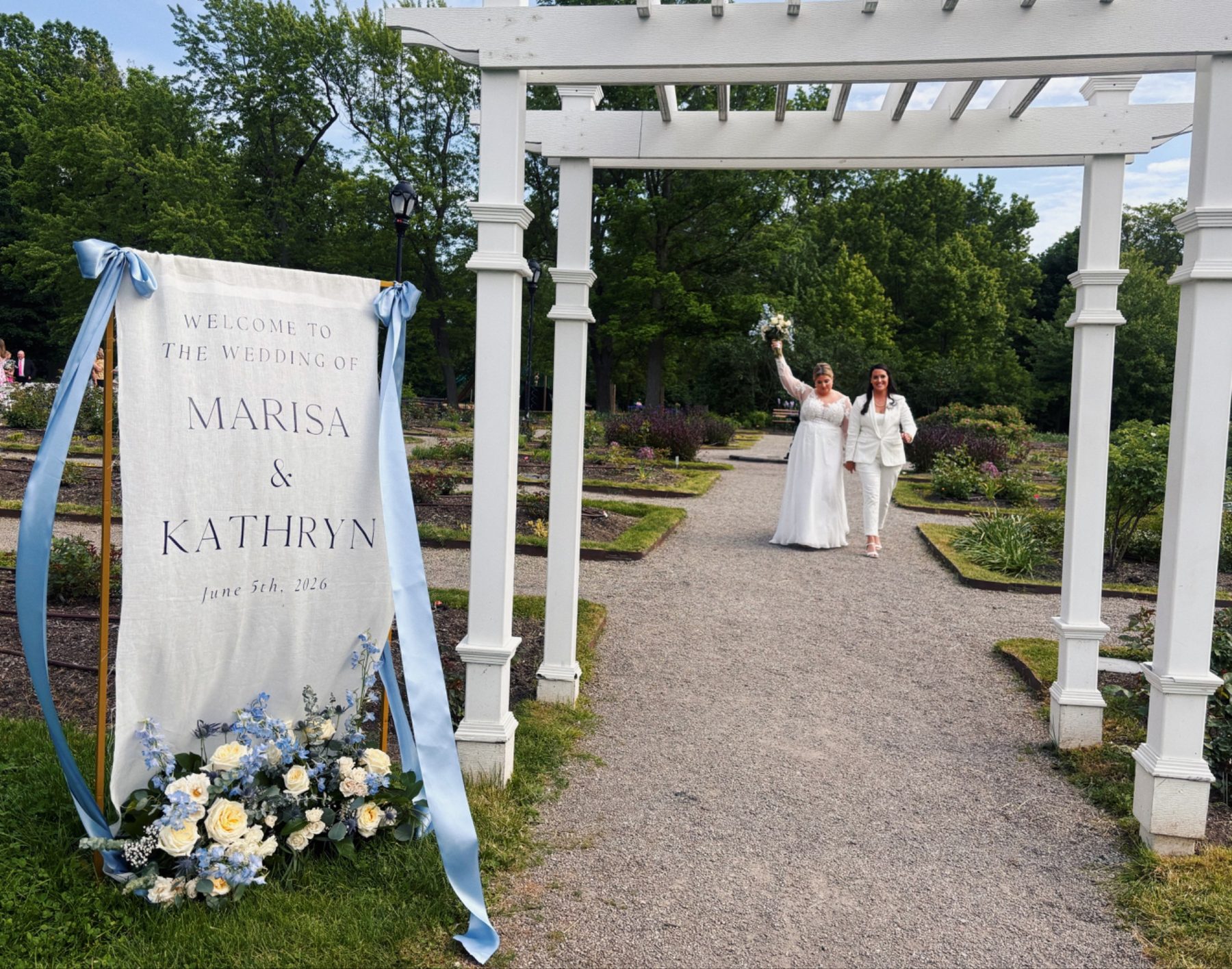 Custom welcome sign for a real Farkas Events wedding, with a bride and her mother walking up the garden path behind it